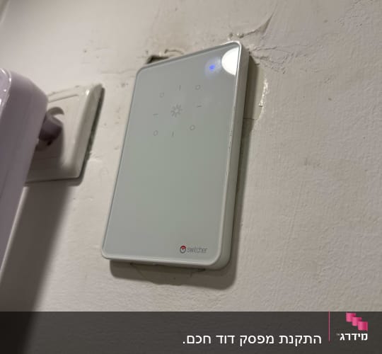 מתג חכם מותקן על קיר עם שקע חשמל